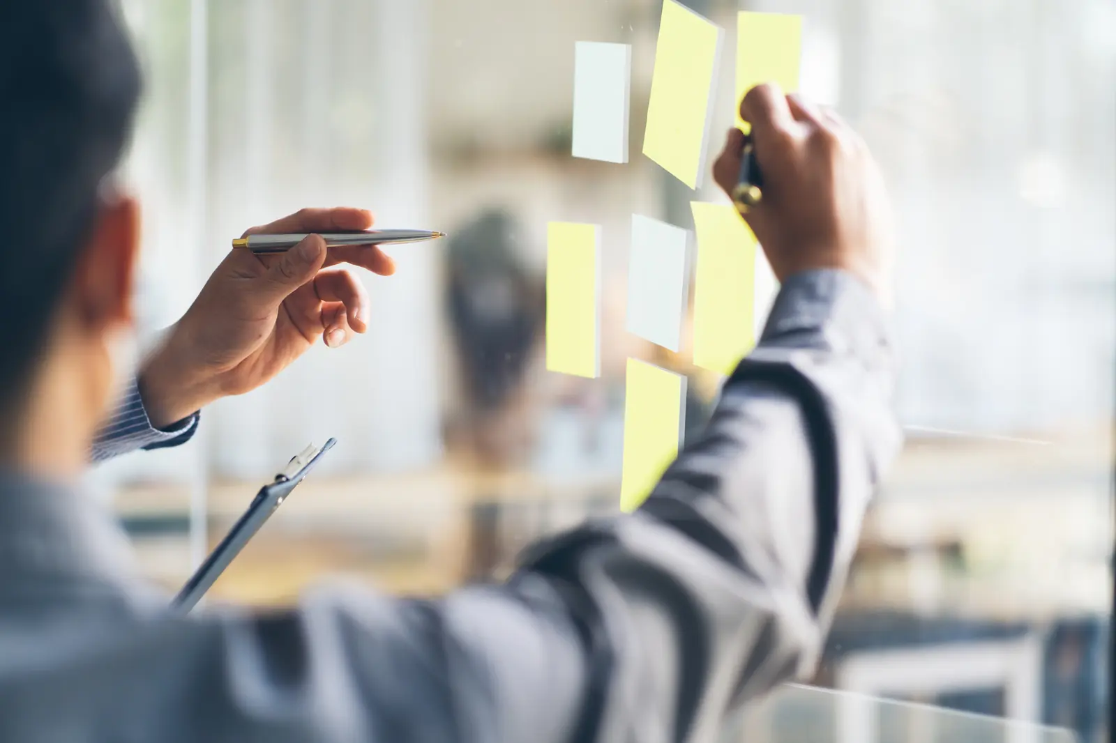 Consultant organisant des notes sur un mur lors d'un atelier de cartographie